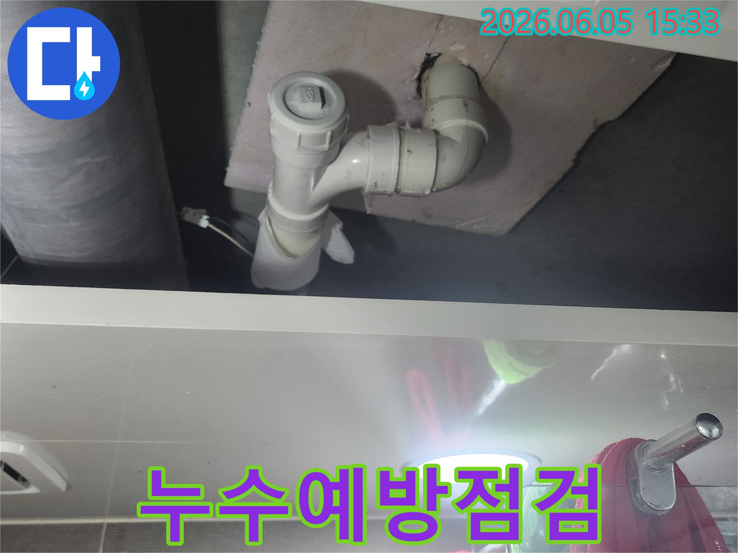 좁은 공간에 위치한 배관의-누수 여부를-밝은 조명으로 확인하는 모습입니다