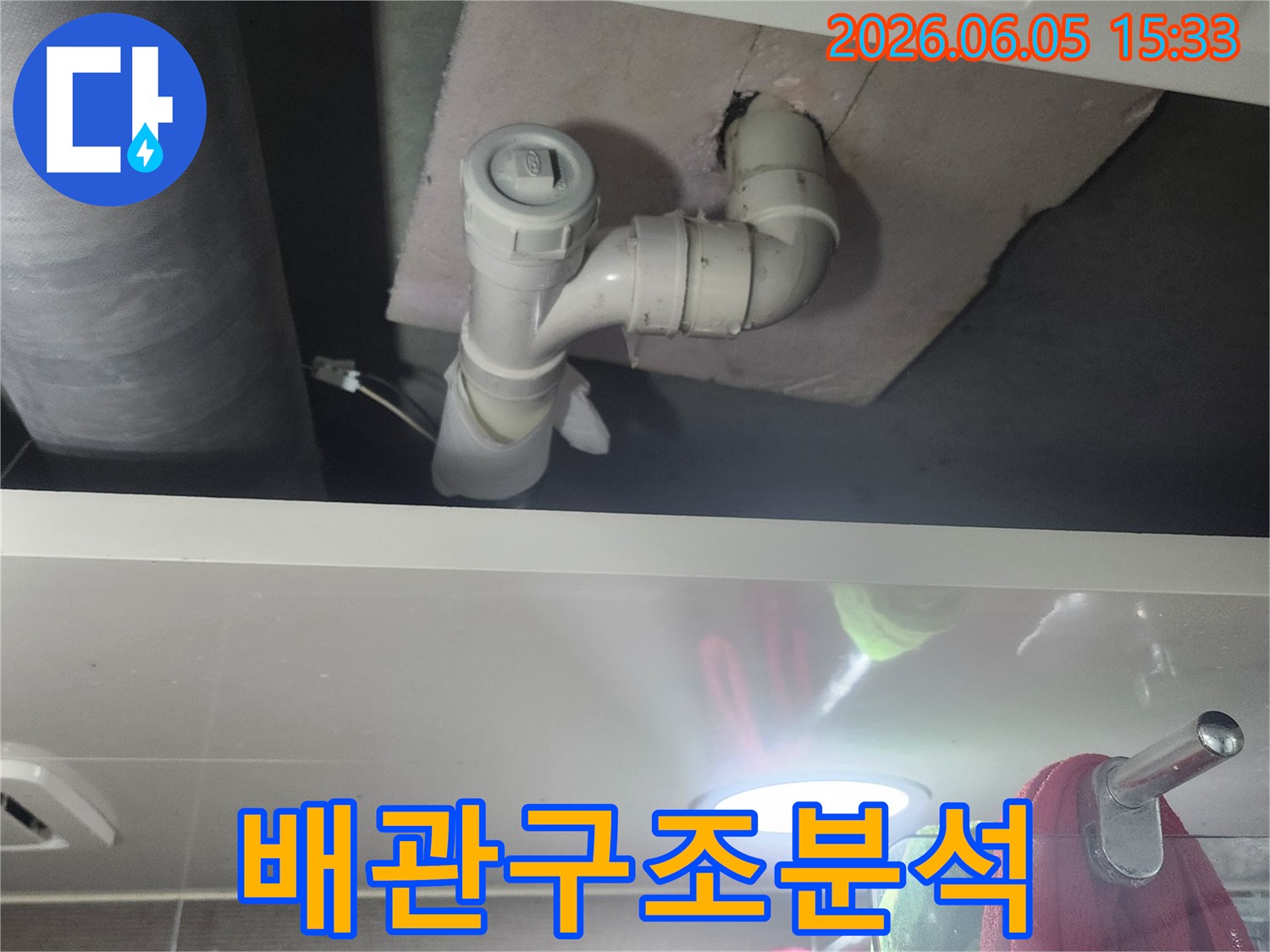 좁은 공간에 위치한 배관의-누수 여부를-밝은 조명으로 확인하는 모습입니다