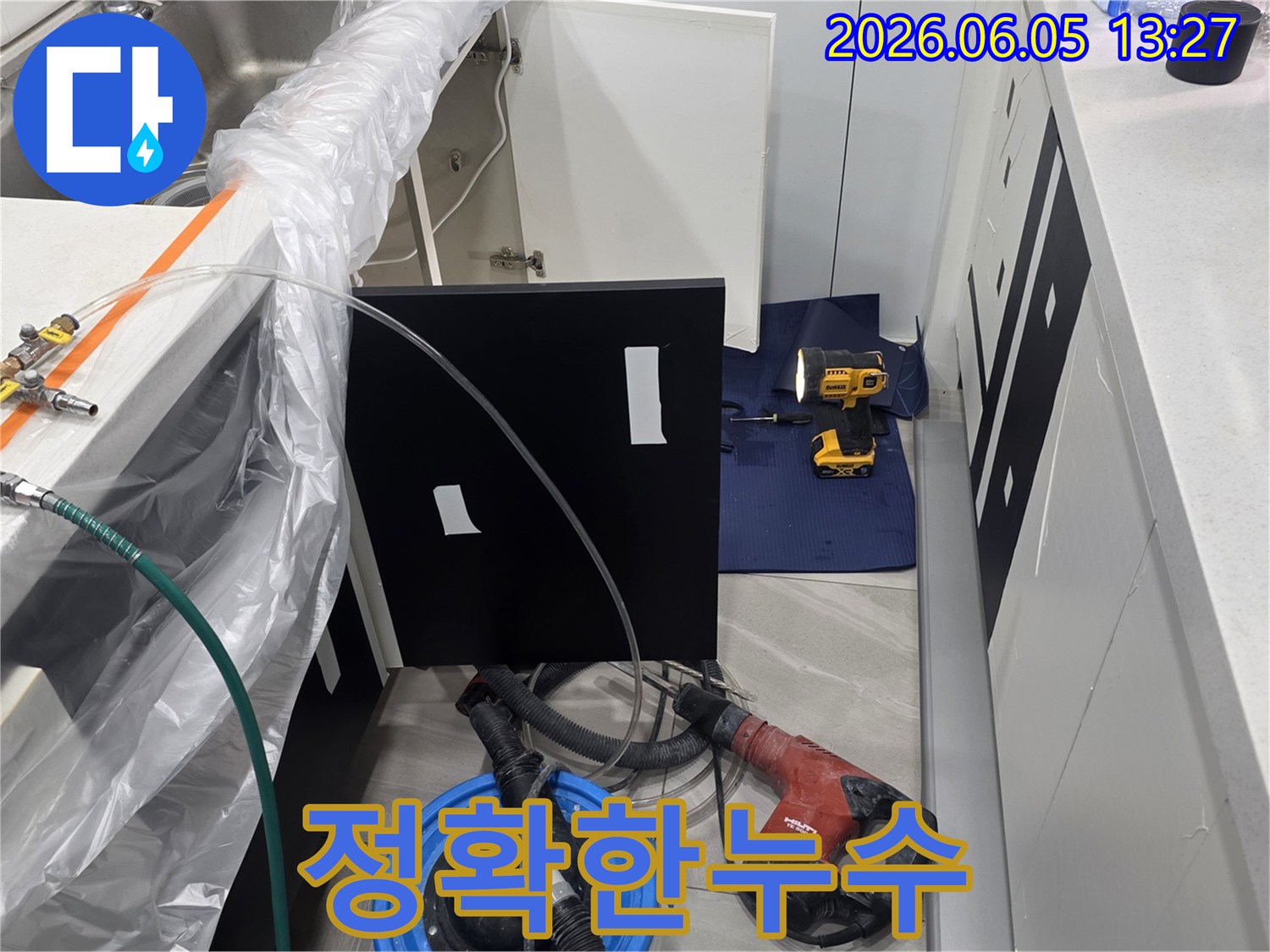 주방 싱크대 아래에서 누수 작업을 진행하며-주변을 보호하고 있는 현장 사진입니다.