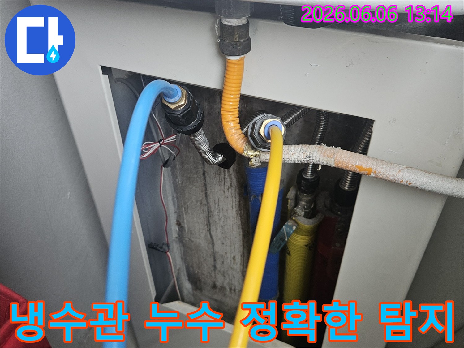 보일러 하단에 연결된 파란색 냉수관의 연결 부위에서-누수 지점을 정밀 장비로 정확하게 탐지하는 과정