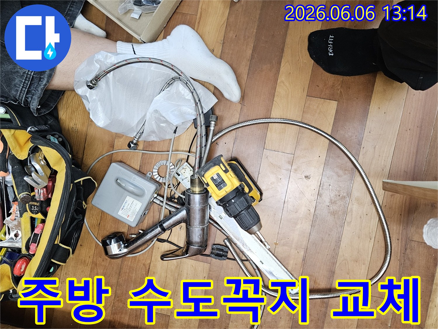 싱크대 수전 교체 작업을 위한-새로운 수도꼭지 부품과-필수 공구들이 바닥에 펼쳐져 있는 현장 사진입니다.