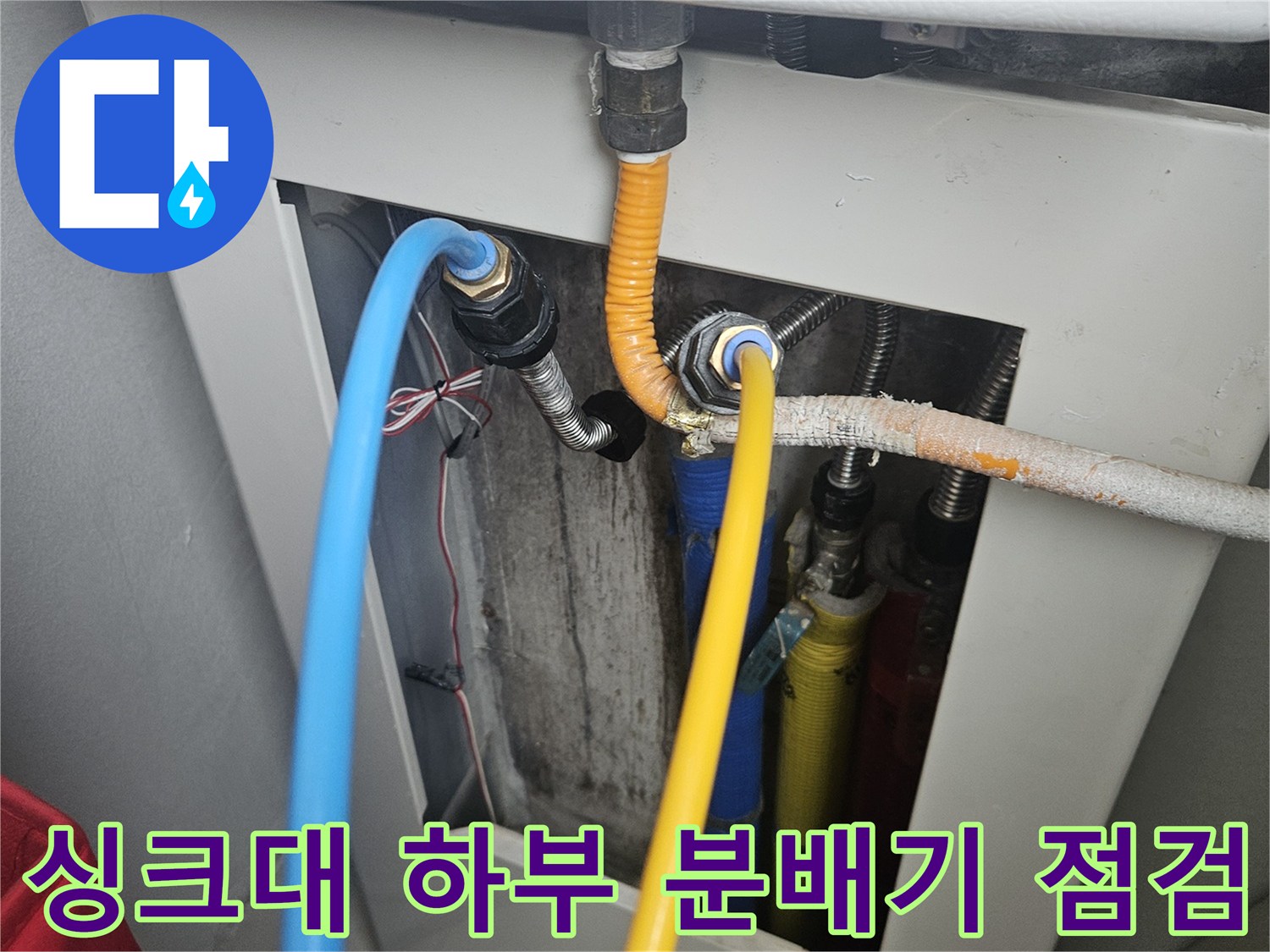 싱크대 하부장 내부에 설치된 난방 분배기와 연결 배관의 모습