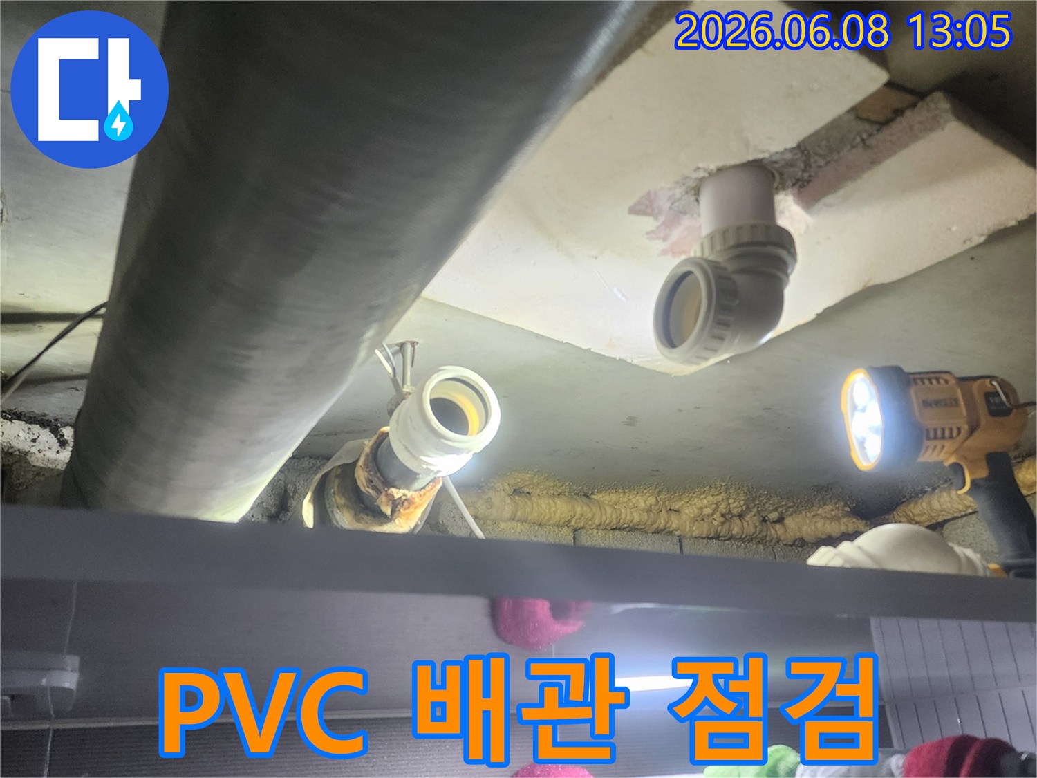 누수-전문가가-어두운-천장-속-PVC-배관의-상태를-점검하고-보수-작업을-준비하는-모습