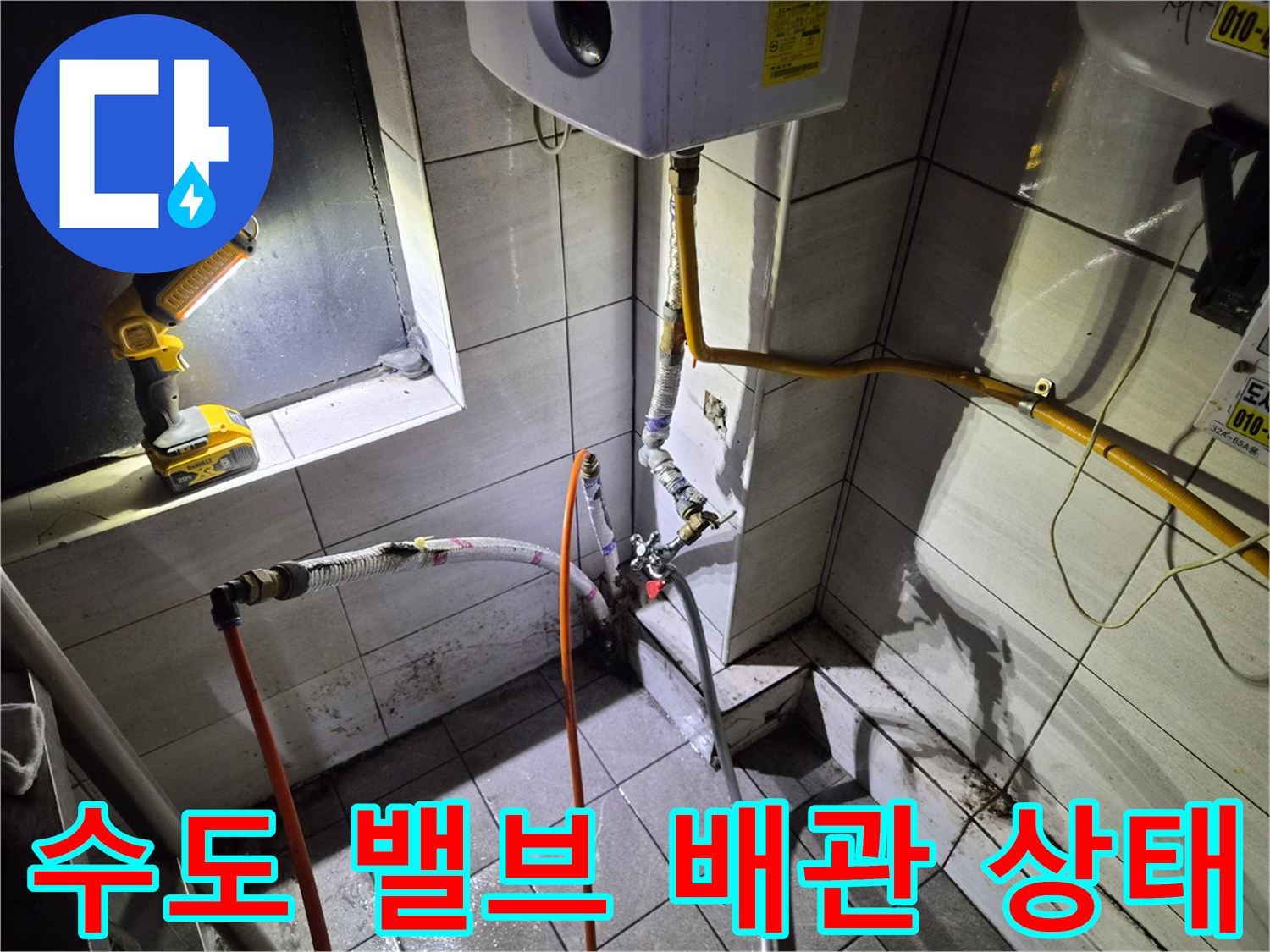 벽면 타일 사이의 배관 연결 부위와 노란색 수도 관로를 촬영한 사진