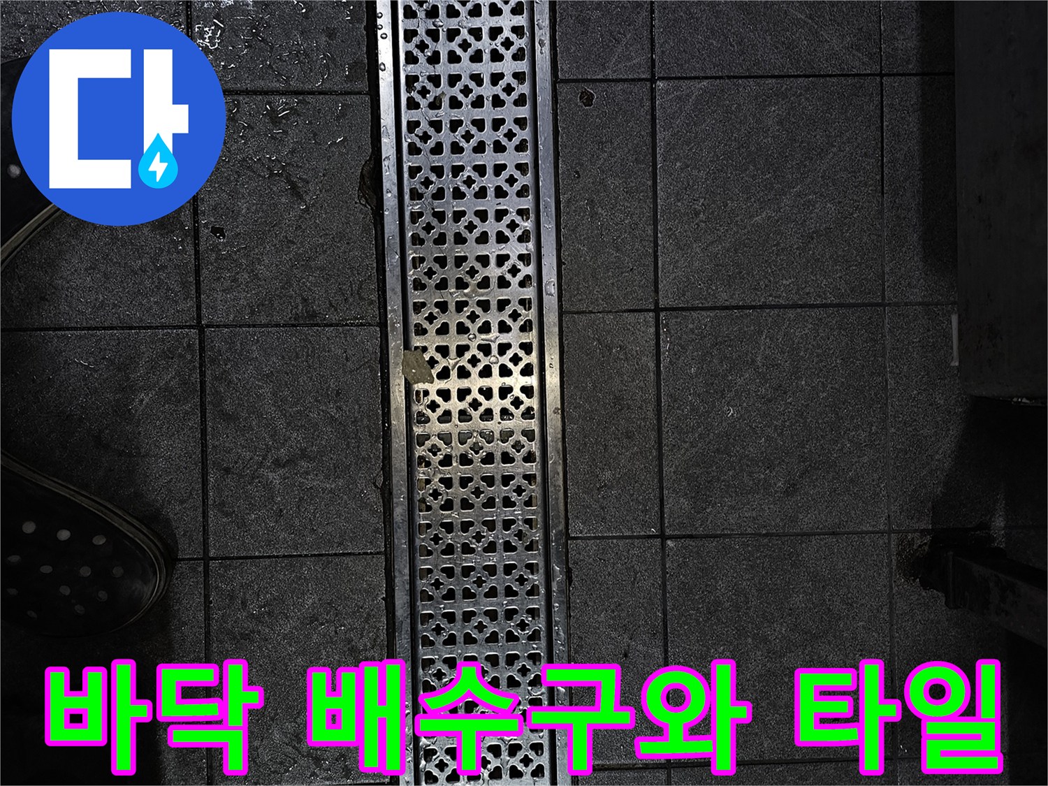상가 매장 바닥의 금속 재질 배수 트렌치와 어두운 색상의 타일 상태