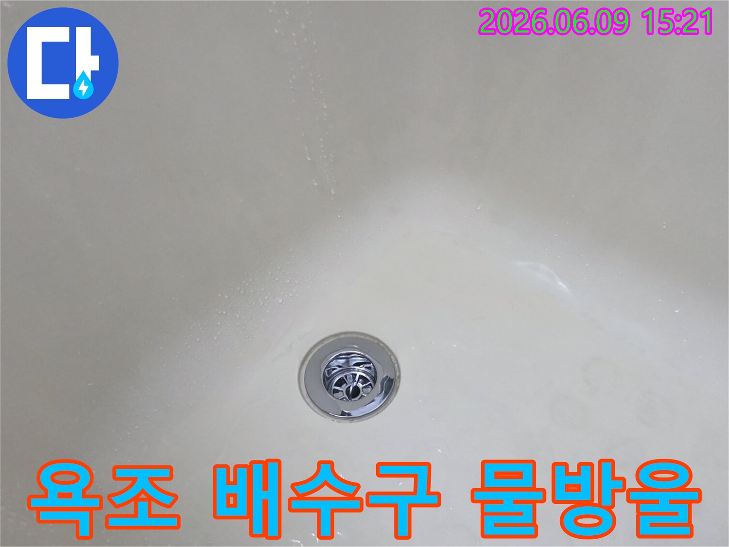 하얀-욕조-바닥에-크롬-도금된-배수구가-보이고-그-주변에-물기가-있는-모습