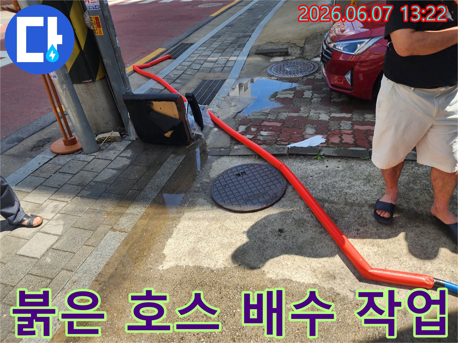 맨홀에서 뻗어 나온-배수 작업을 위한 붉은색 호스 전경