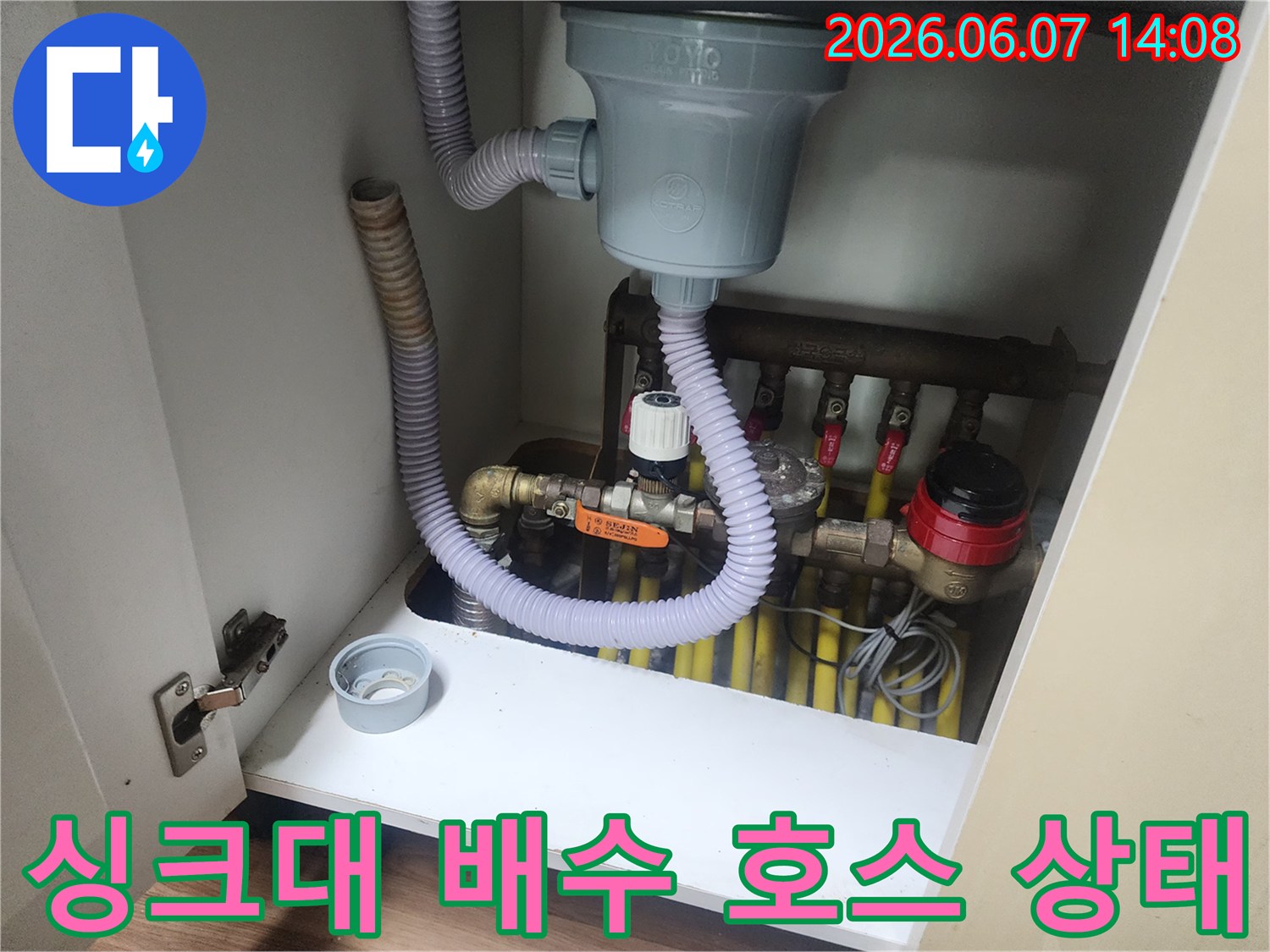 회색 주름관과 밸브가 연결된 싱크대 하단 배관 사진입니다.