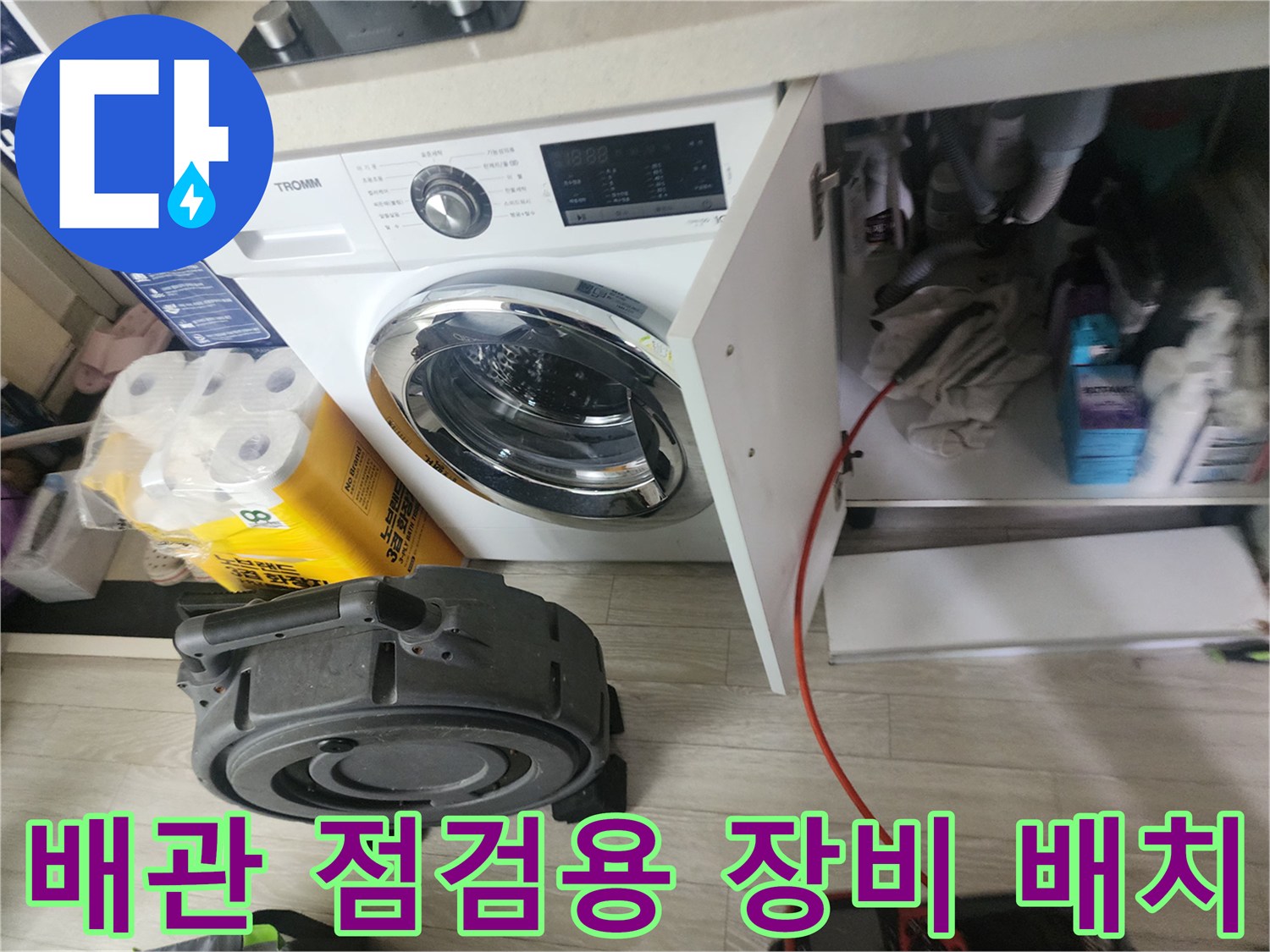 싱크대 아래 배관 근처에 놓인 배관 점검용 릴 장비