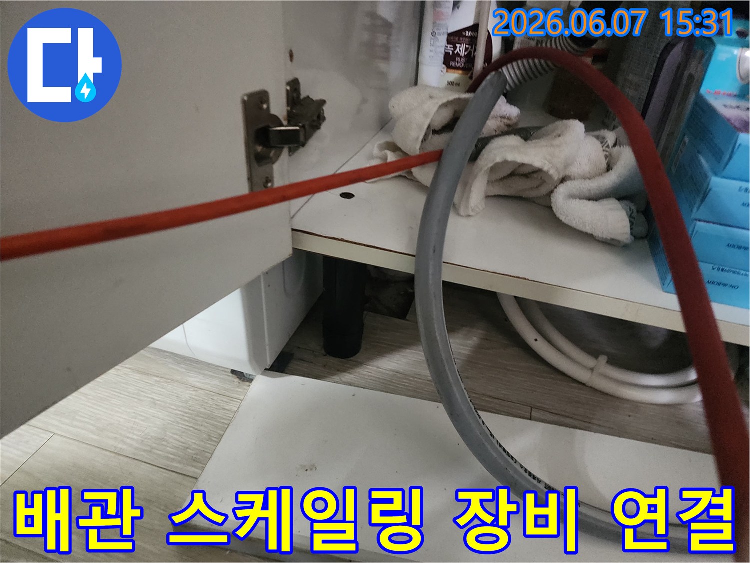 하부장 배관 옆에 놓인 붉은색 호스와 회색 배관 장비