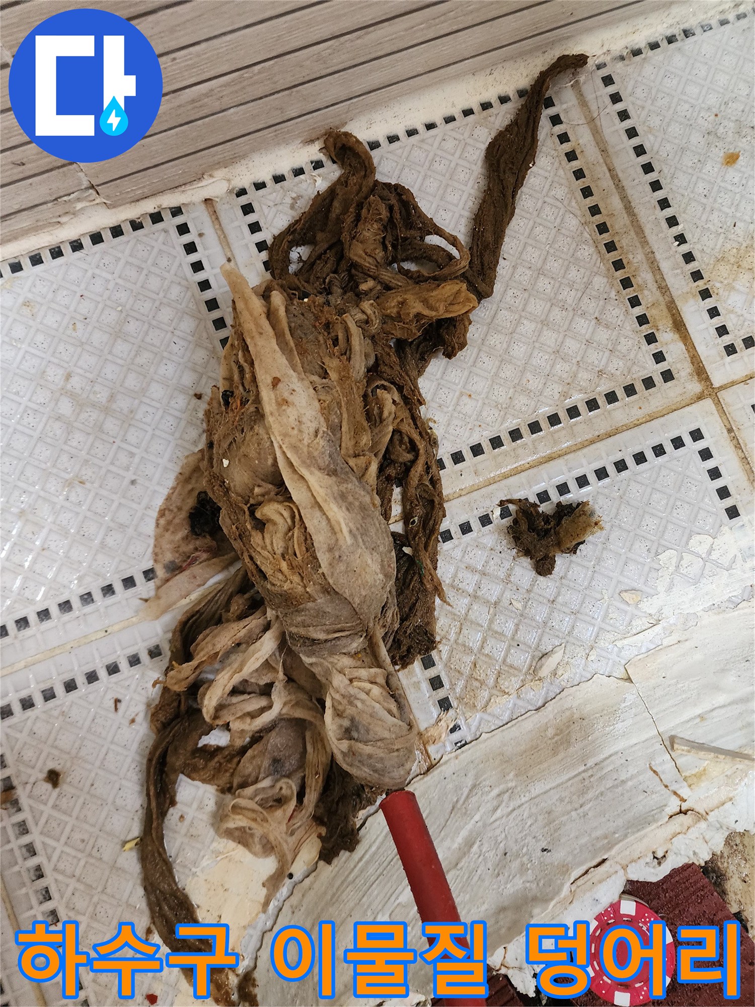 화장실 바닥 타일 위로 인양된 거대한 머리카락과 섬유 슬러지 뭉치