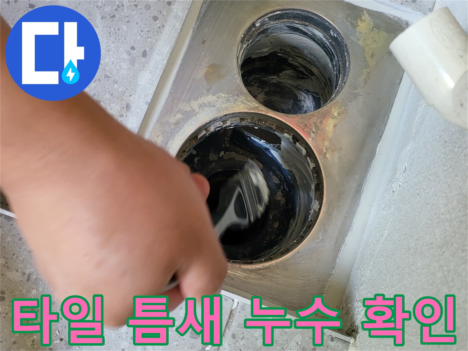 세탁실 타일과 배수구 사이의 벌어진 틈을 점검하는 장면