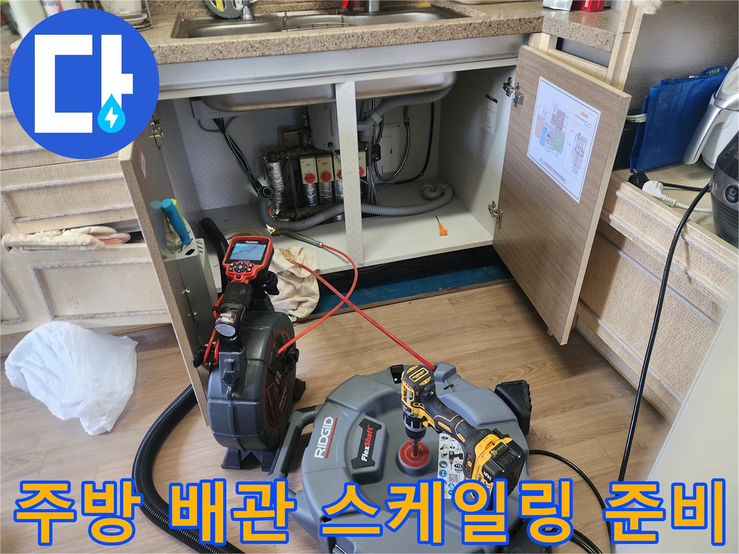 싱크대 밑 하부장 공간에 설치된 전문적인 배관 청소용 장비 세트