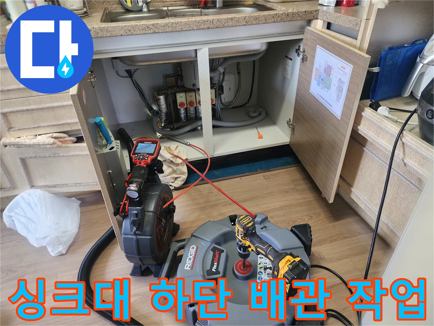 주방 싱크대 하부장 아래에 배치된 배관 내시경 카메라와 석션 장비