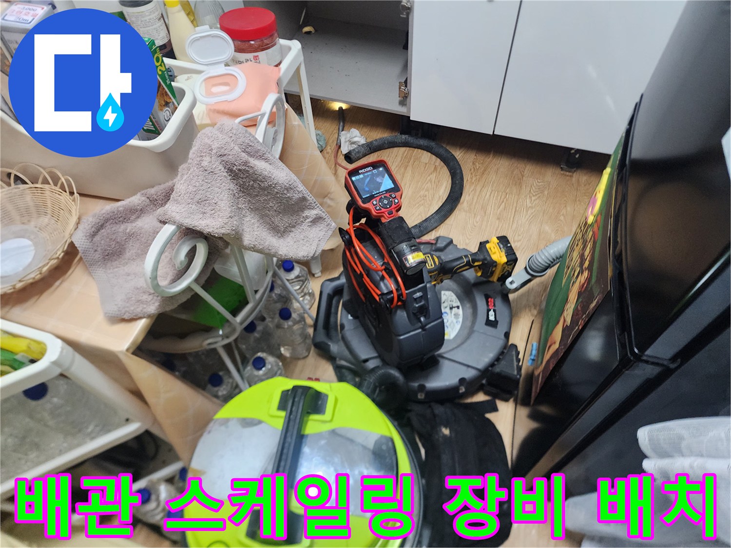 싱크대 아래 공간에 놓인 배관 청소용 전문 기계와 도구들
