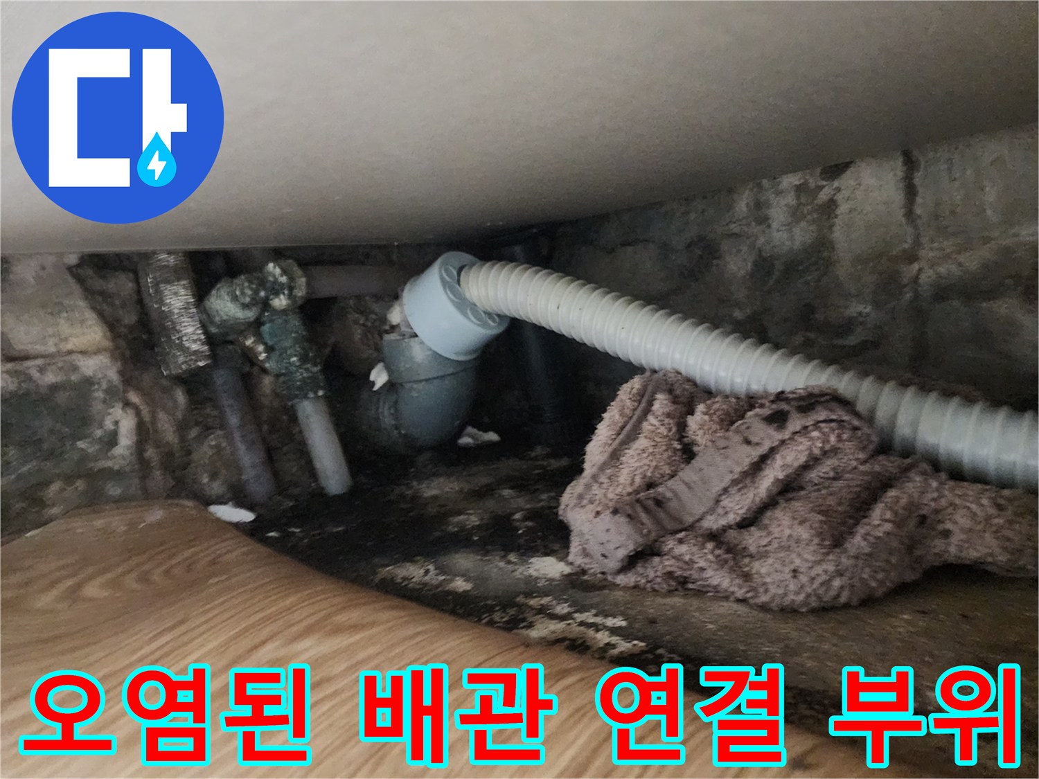 싱크대 하부장 내부의 오염된 배관과 젖은 바닥재