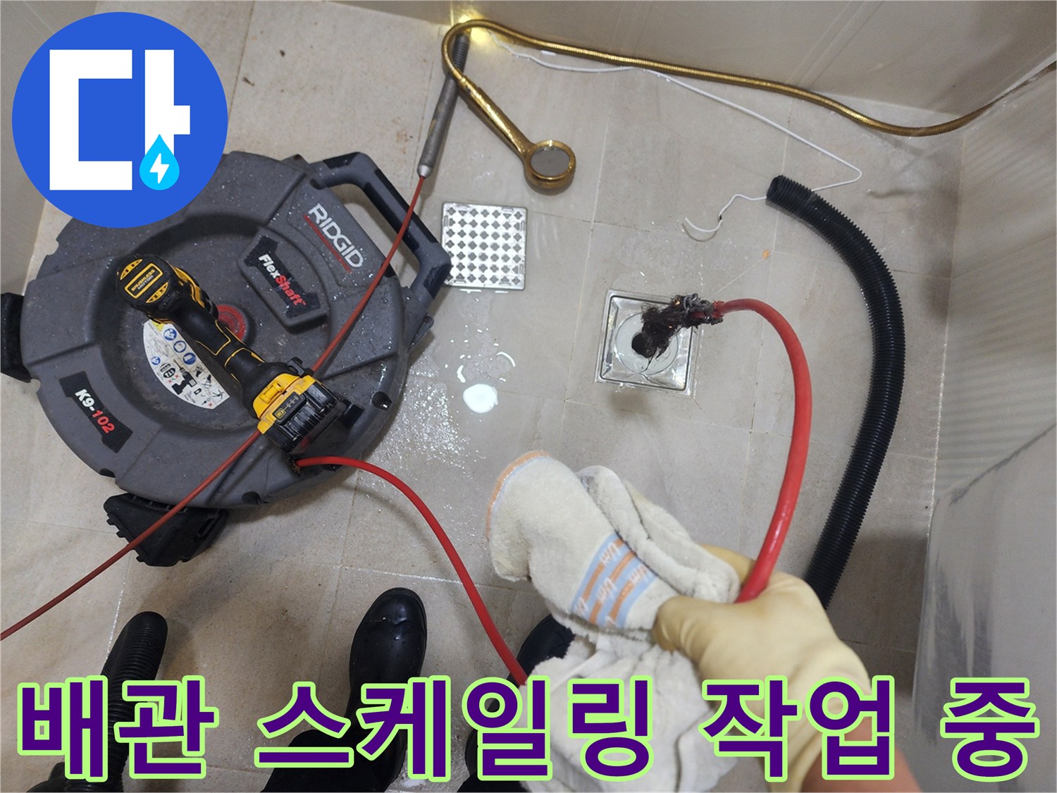 화장실 바닥 배수구에 전문 장비를 사용하여 이물질을 제거하는 장면