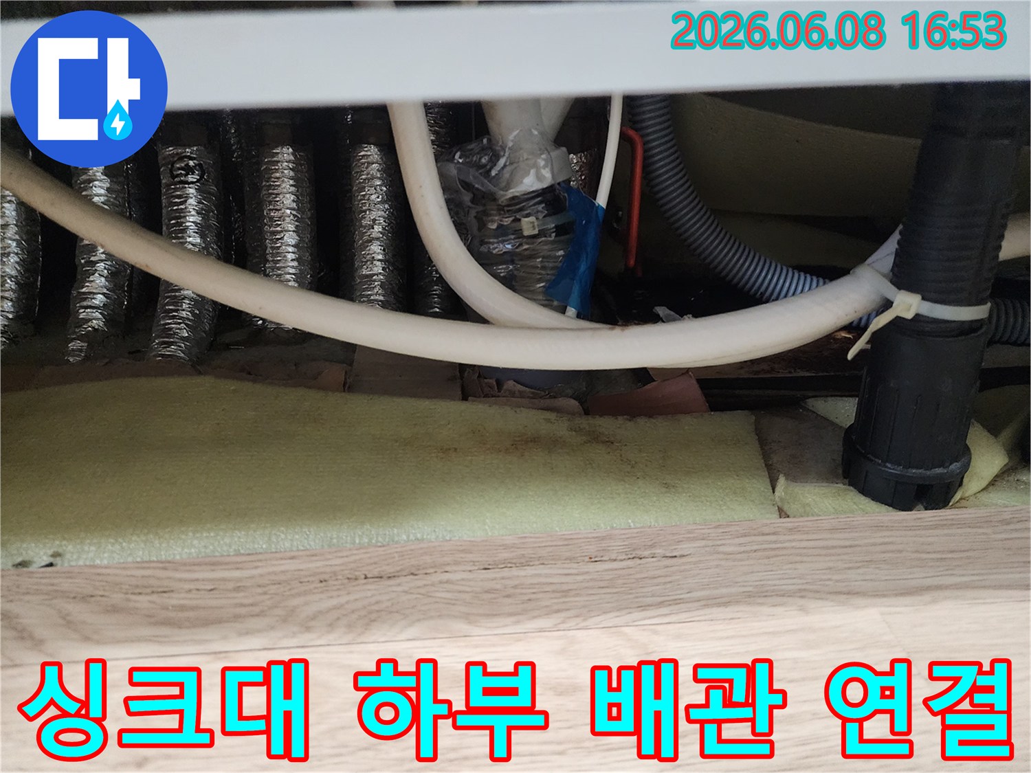 랩과 타이로 임시 고정된 싱크대 배관 연결부 근접 촬영