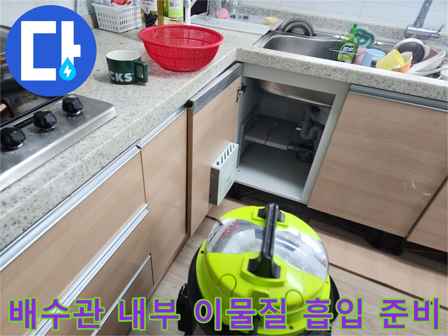 석션기를 사용하여 싱크대 배수관의 이물질을 빨아들이는 작업 장면