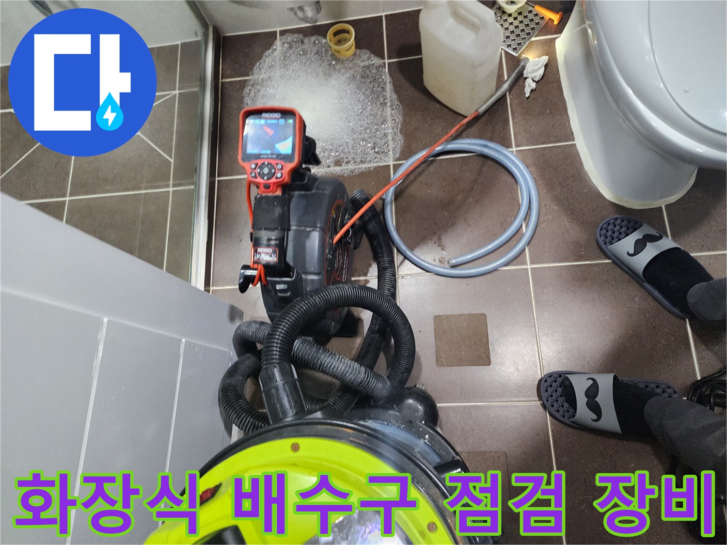 바닥 타일 위에 놓인 배관 내시경 모니터와 흡입용 진공 청소기 호스