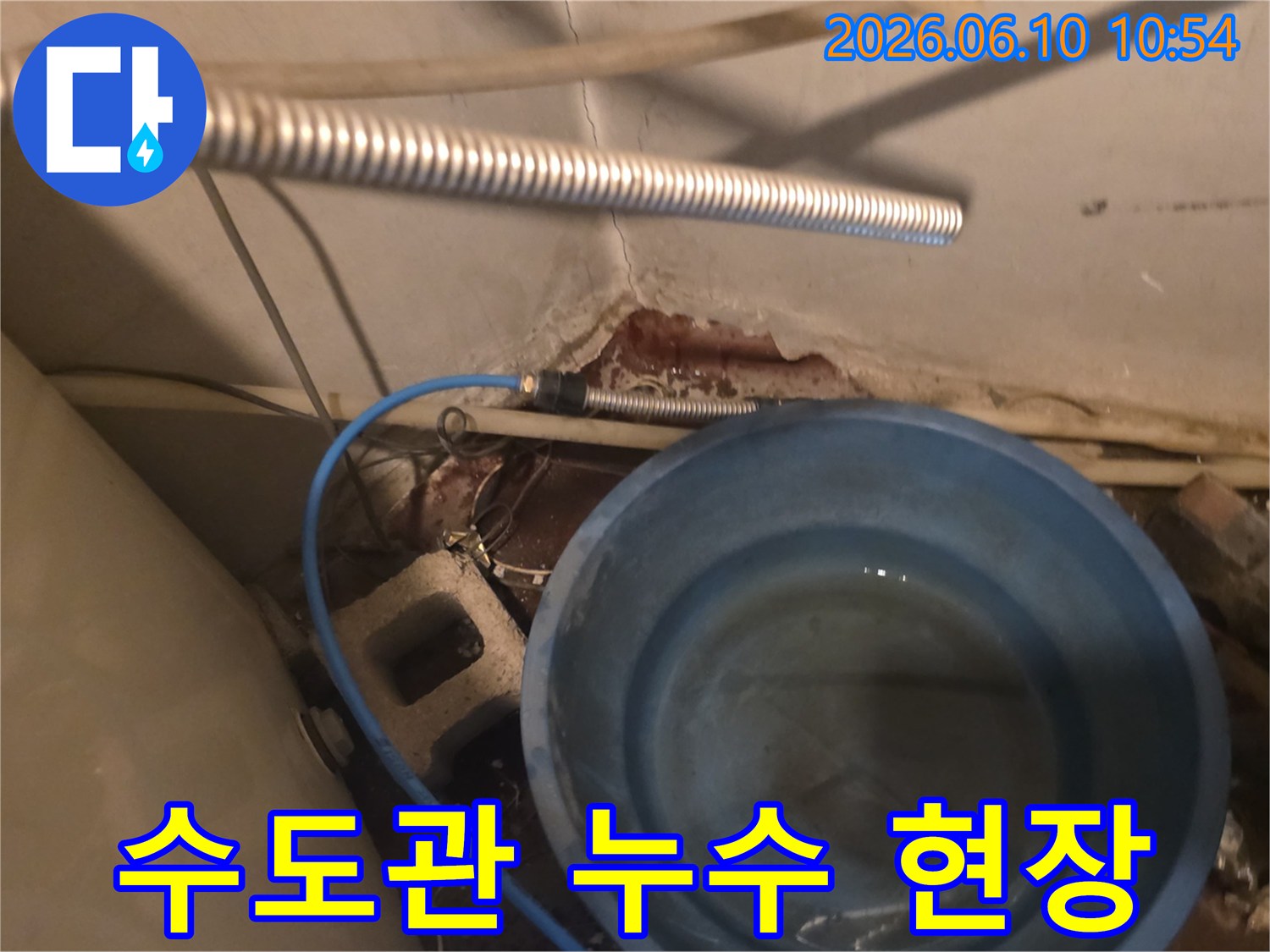 수도관 누수로 인해-콘크리트 벽면이 부식되고-물이 양동이에 고이는 모습