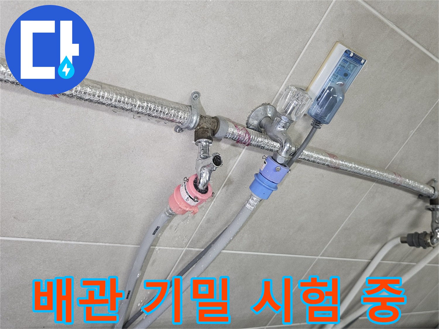 세탁실 벽면-연결된 호스와 압력계로 배관 상태를 점검하는 장면