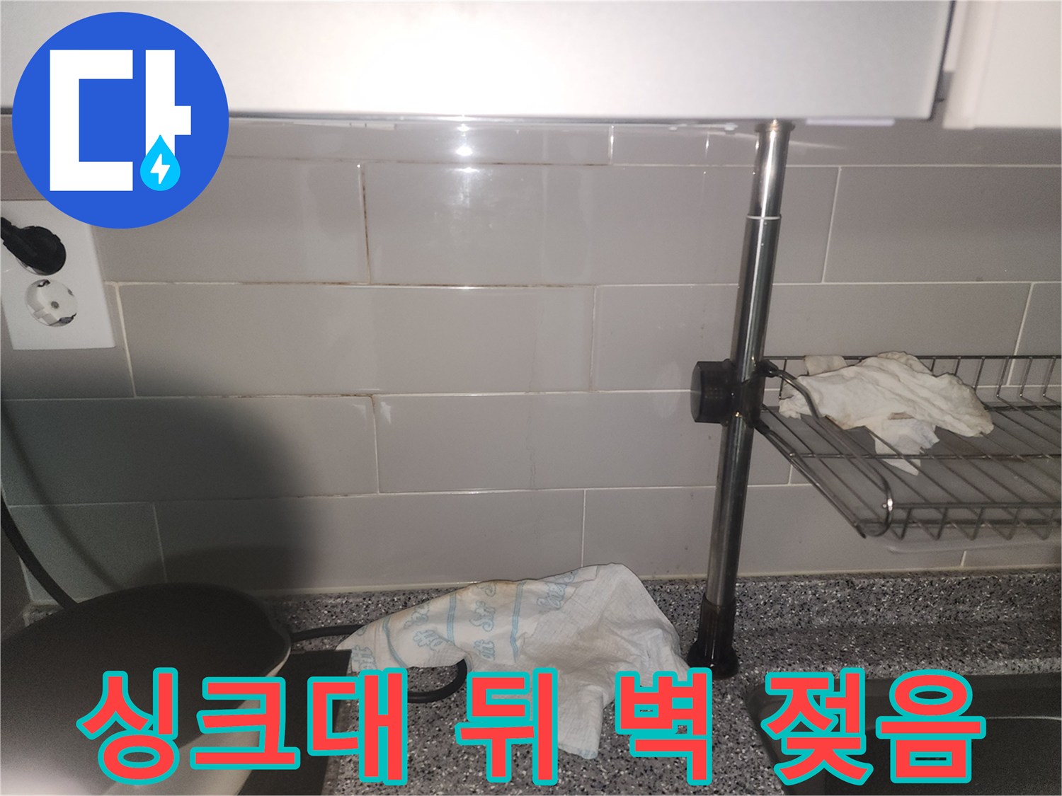 싱크대 뒤편 타일 벽면에-물기가 스며들어-젖어있는 모습이 포착된 사진