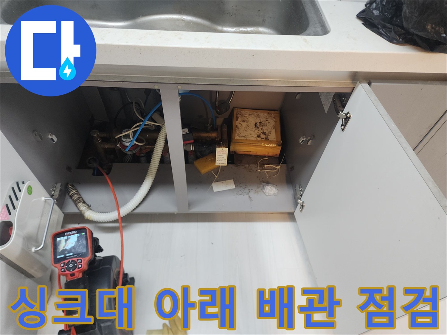 싱크대 하부장 내부의 복잡한 배관 구조와 내시경 장비 배치