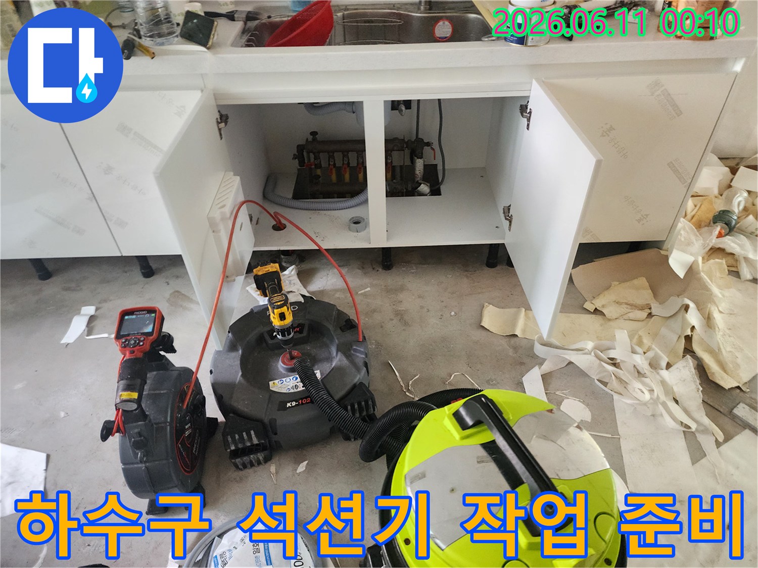 싱크대 아래 배관 주변에 배치된 강력 석션 장비와 청소 도구