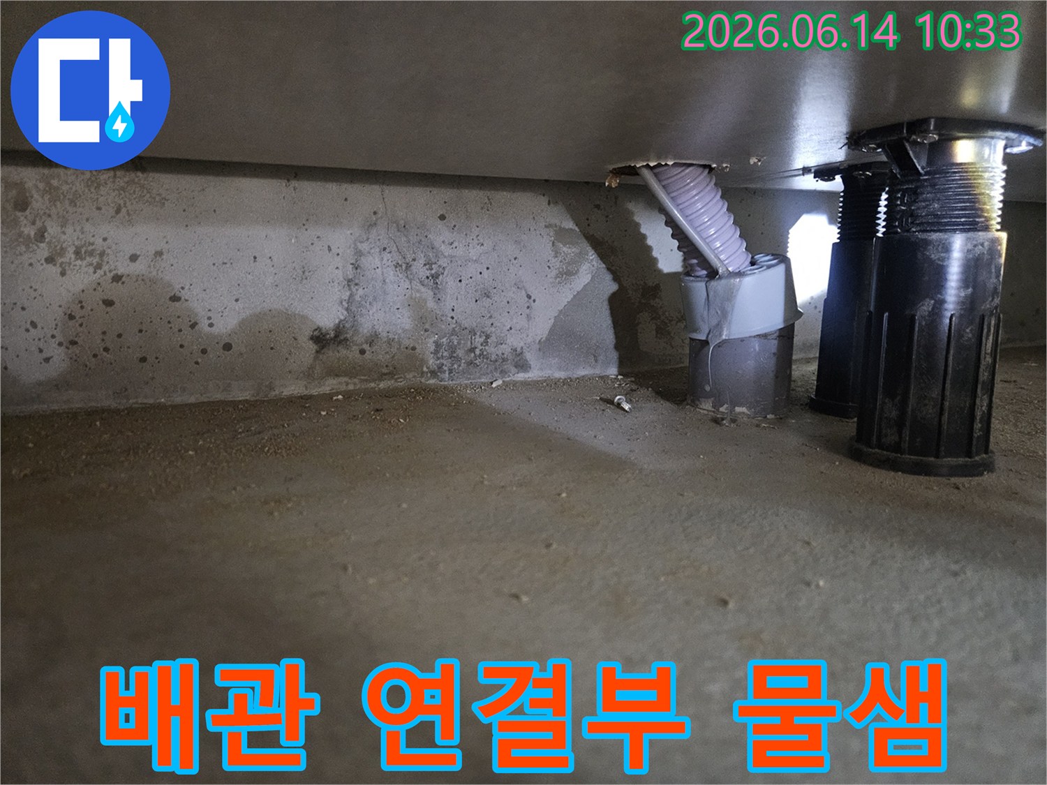 이 이미지는 지하 공간에 설치된 배관 연결부 주변에서-물이 새어 나와 벽면과 바닥을 적시고 있는 현장을 보여줍니다.