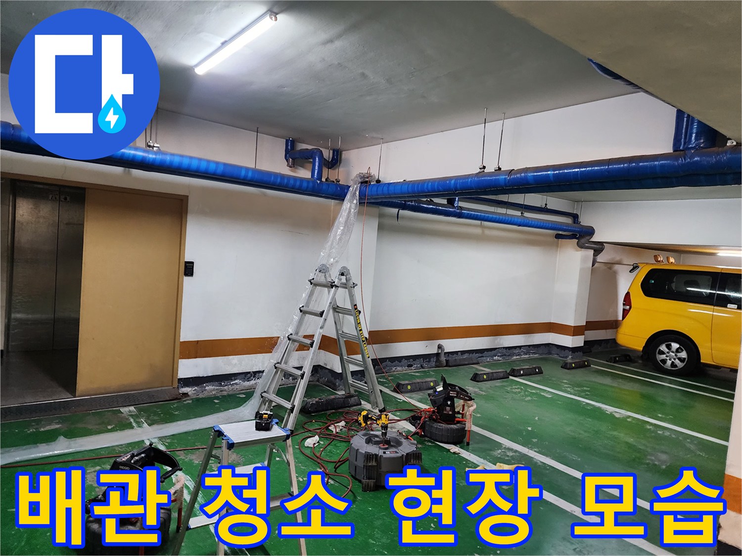 지하주차장 천장 배관 아래에 배치된 전문 세척 장비와 작업 도구들