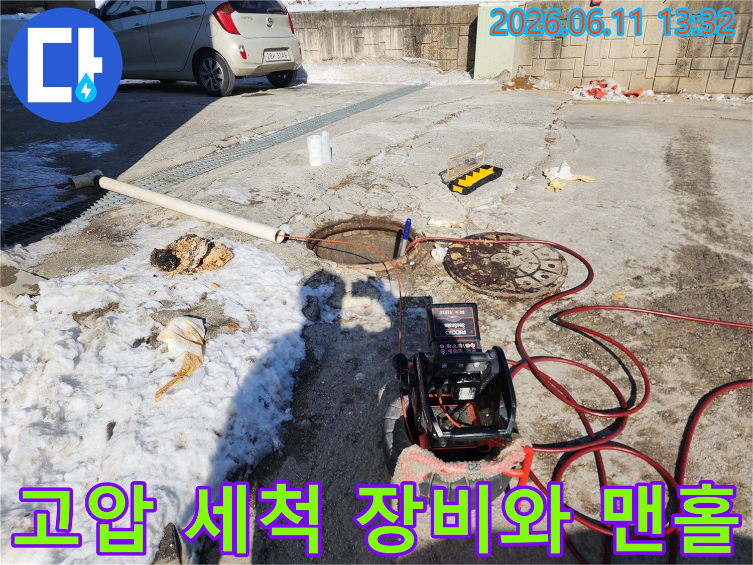 맨홀 뚜껑 옆에 놓인 배관 세척용 모니터와 호스 연결 상태