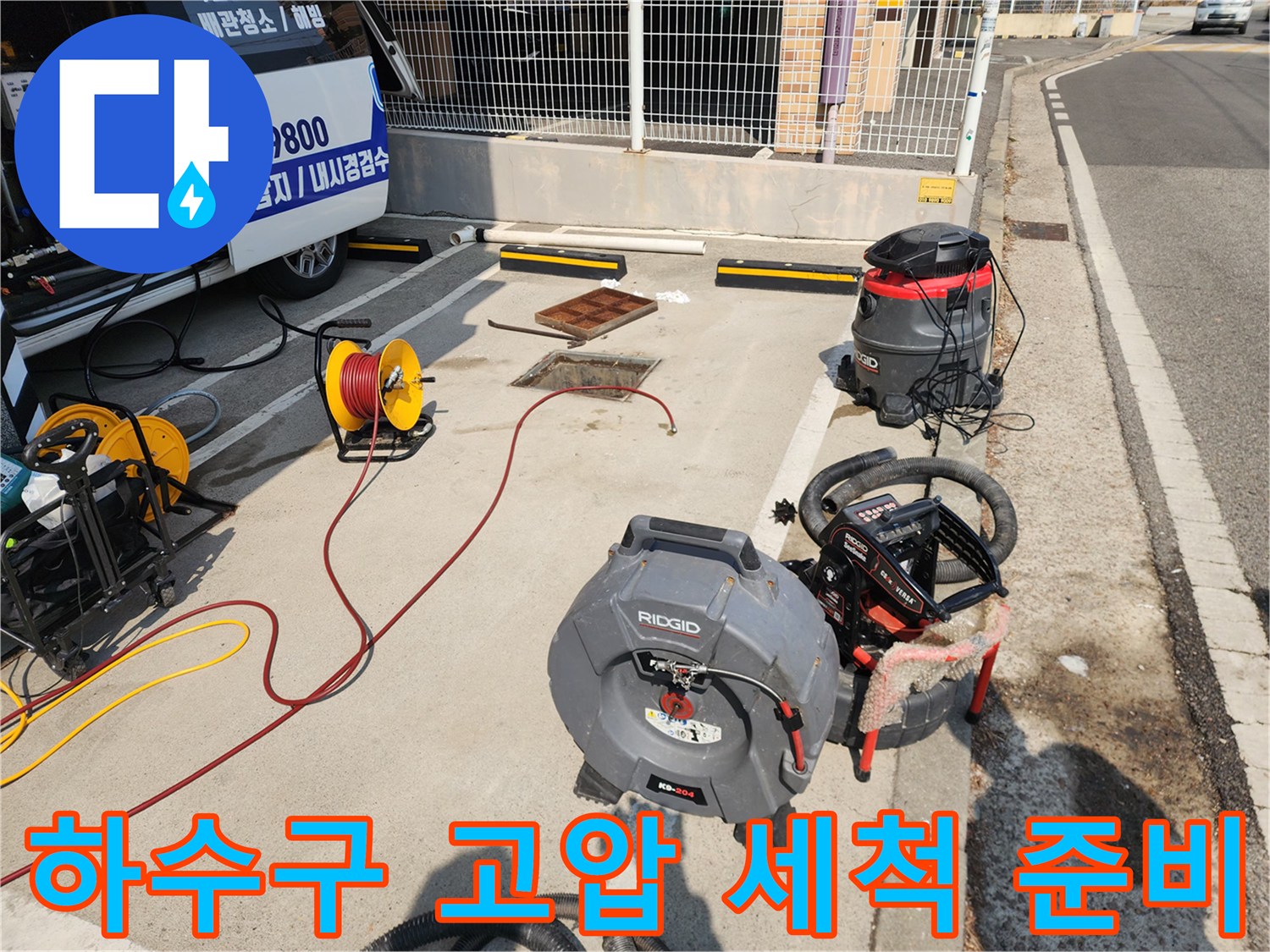 맨홀 주변에 배치된 고압 호스 릴과 청소 장비의 모습입니다.