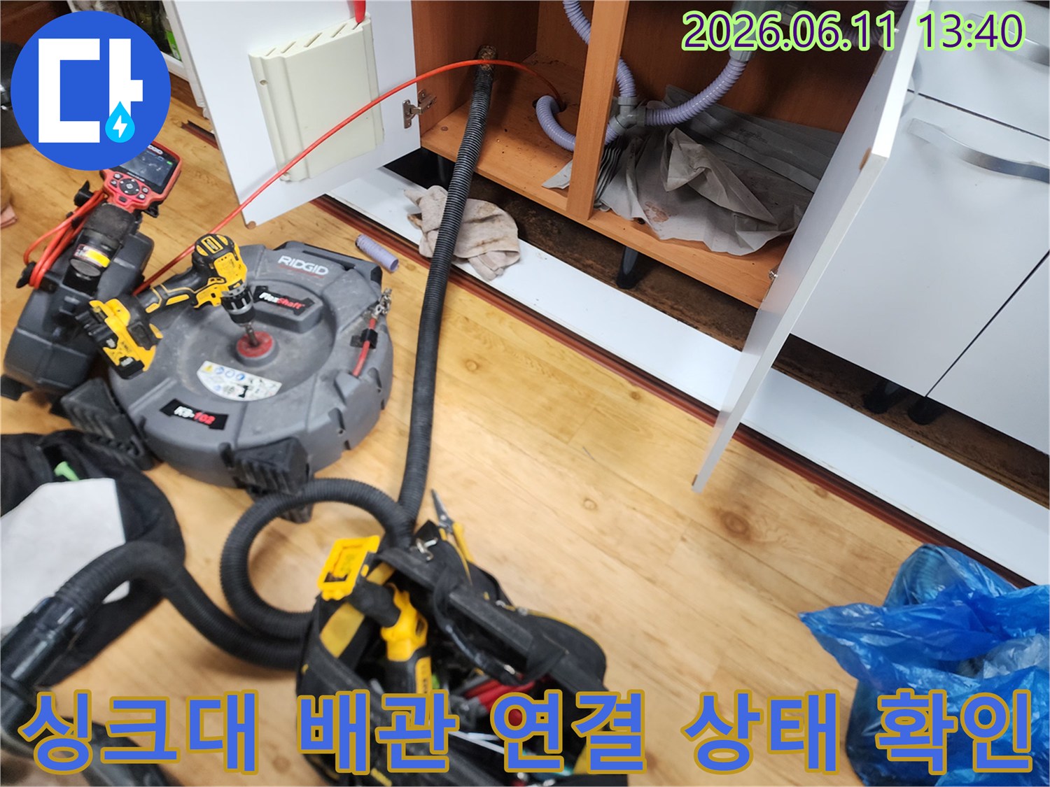싱크대 하부장 배관과 전문 청소 장비가 연결되어 작업 중인 모습입니다.