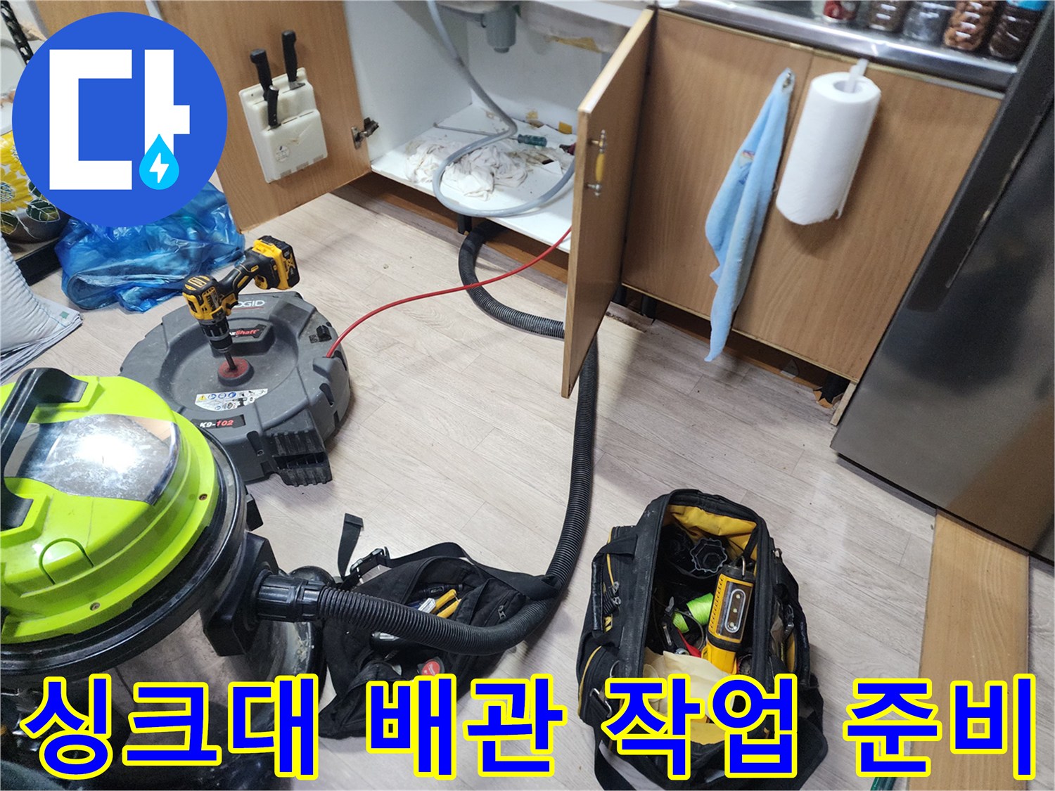 작업을 위해 싱크대 하부장에 배치된 전문 청소 장비들