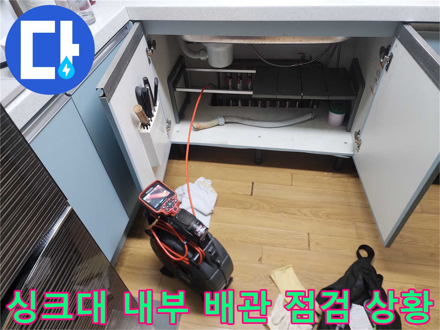 중곡동 현장 싱크대 하부장 내부에 설치된 배수 호스와 작업 장비들