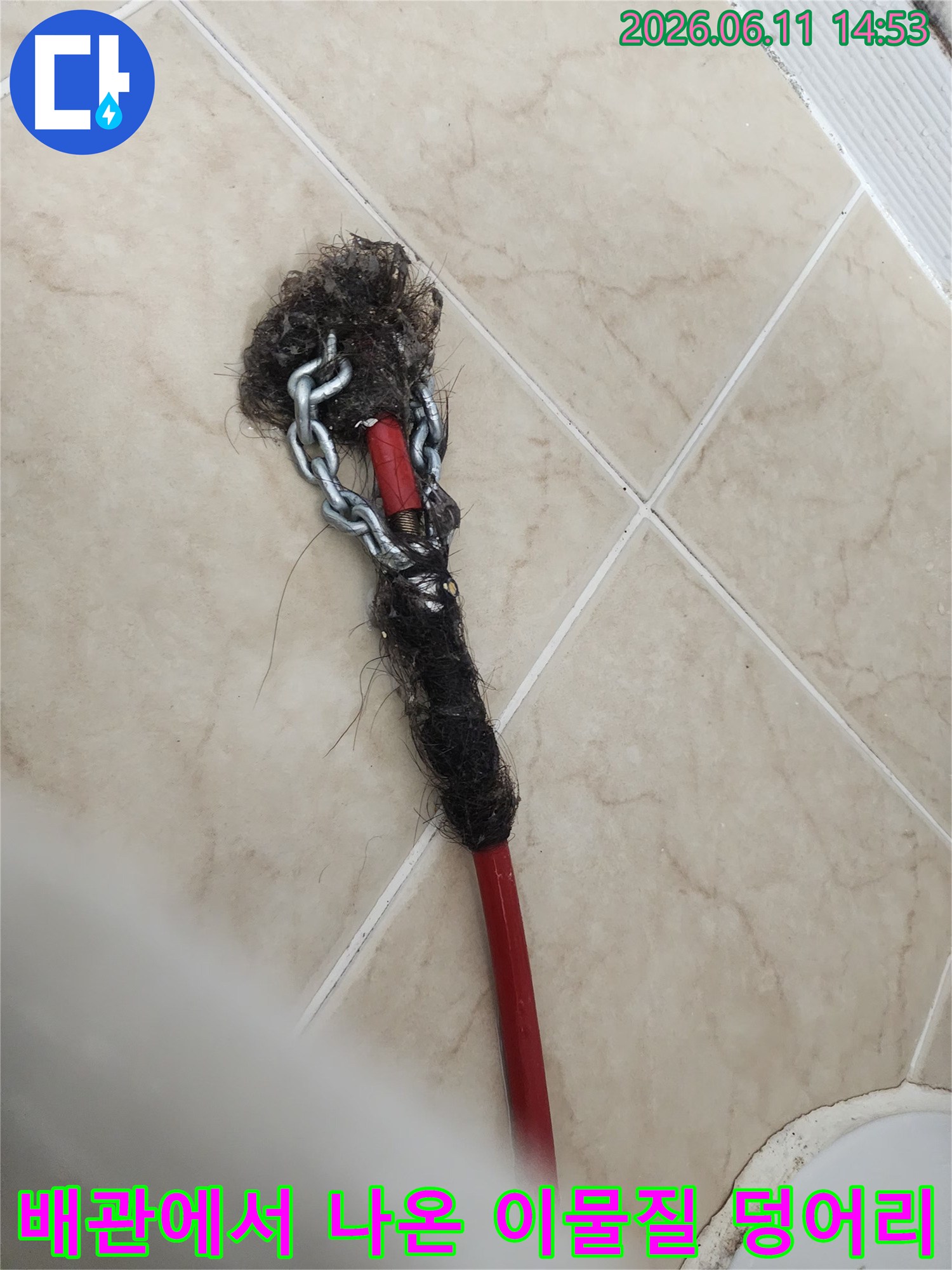 붉은색 장비 끝에 걸려 나온 머리카락과 기름 슬러지 뭉치