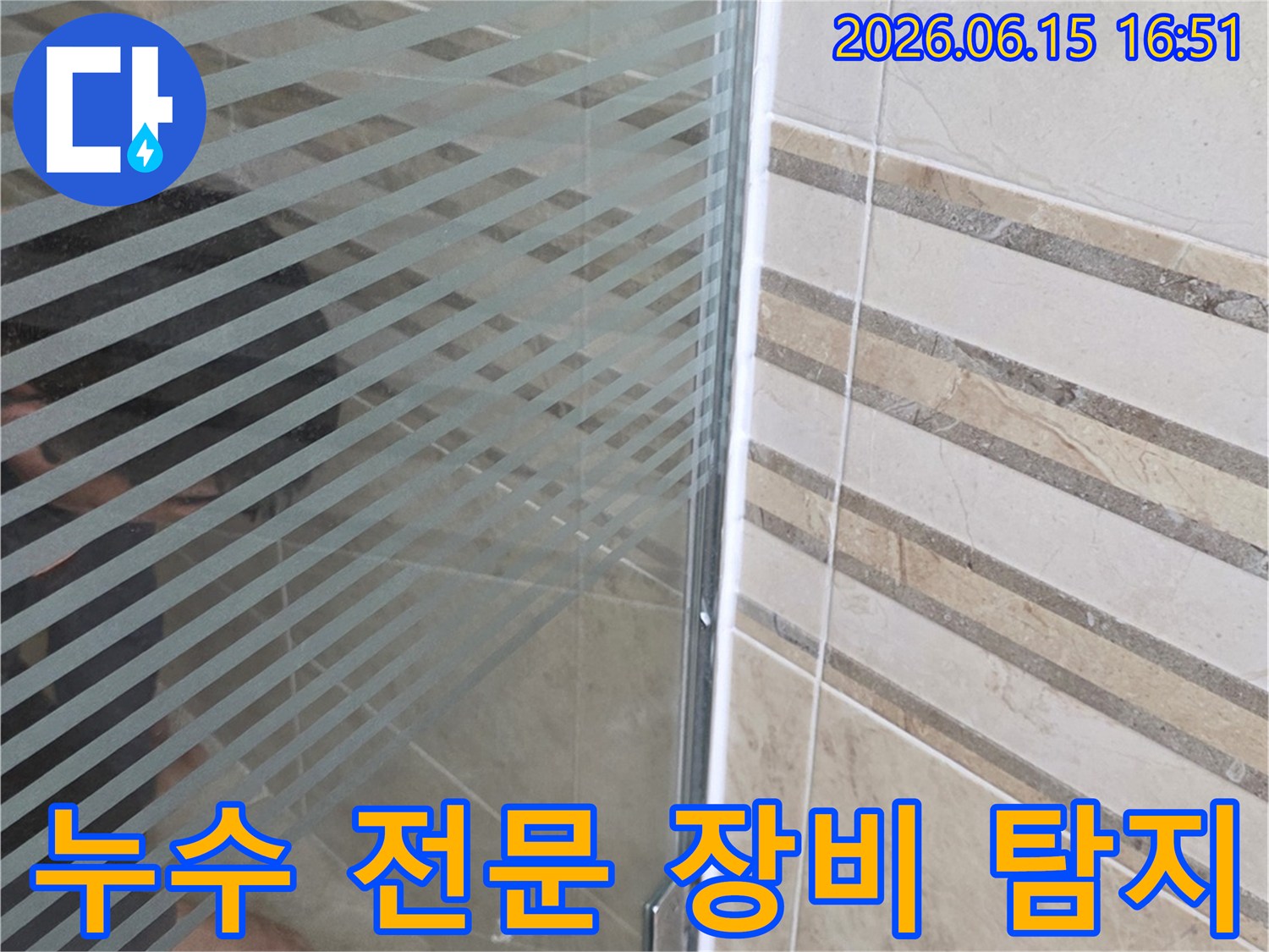 안양 아파트 욕실-샤워 부스 바닥의-누수 지점을-전문 장비로 탐지하며-손으로 가리키는 모습