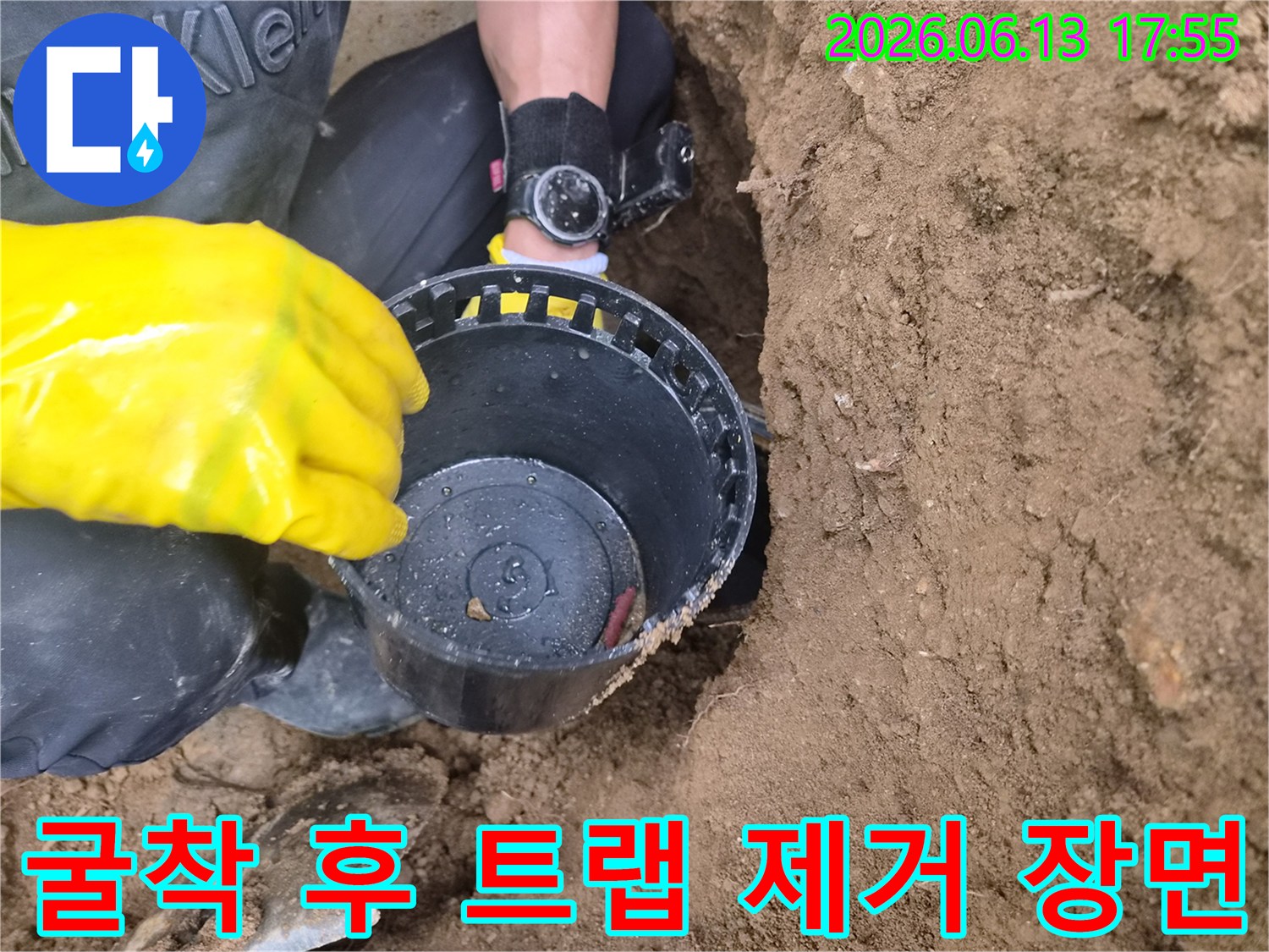 흙 속에서 꺼낸 오염된 소재구 트랩을 작업자가 손으로 잡고 있는 모습