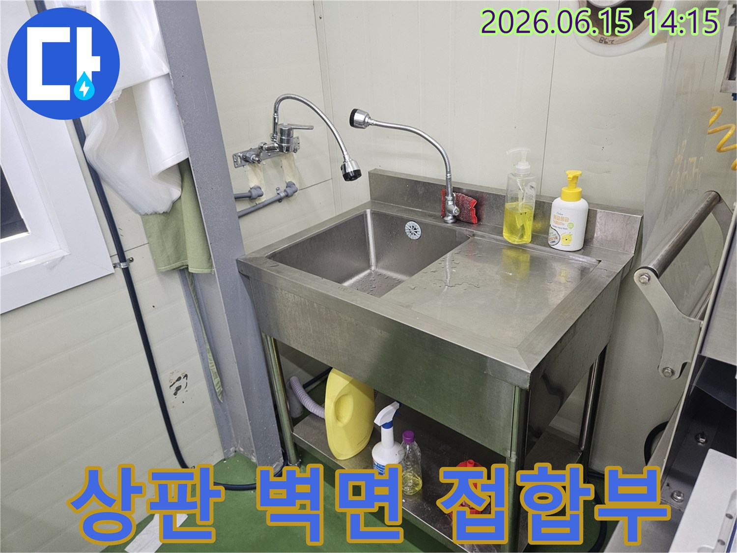 스테인리스-싱크대-상판과-벽면-접합부에서-물이-새는-흔적을-점검하는-누수-전문가의-모습