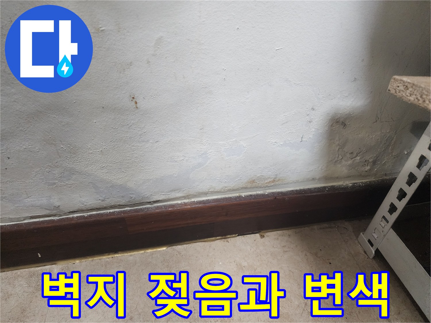 벽 하단부 벽지가 물에 젖어 변색되고 얼룩이 생긴 누수 증상 사진입니다.