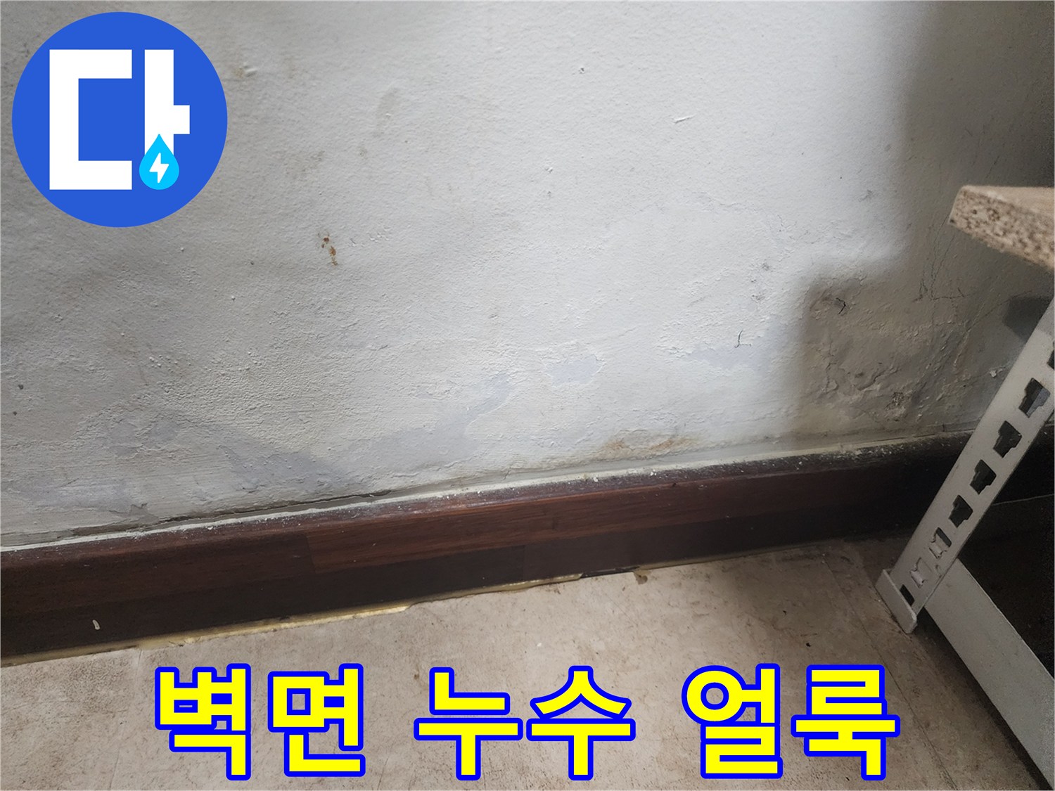 벽 하단부에 물이 스며들어 벽지가 젖고 곰팡이가 피어있는 누수 피해 현장 사진입니다.
