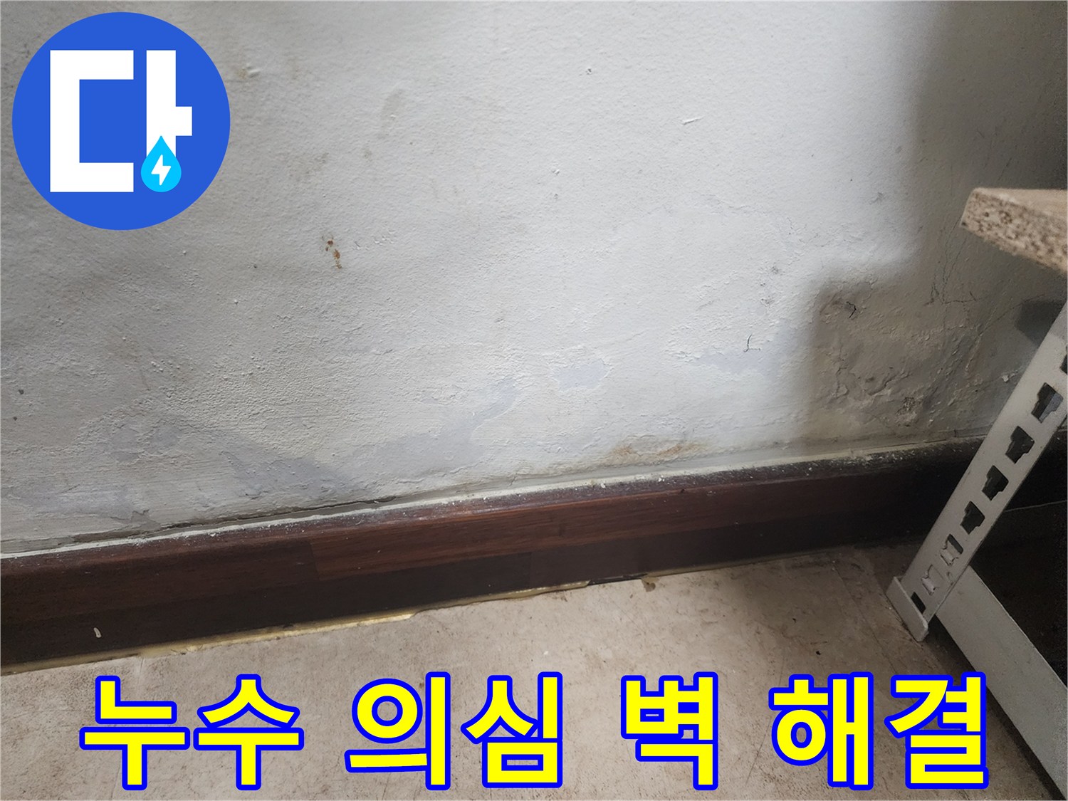 벽 하단부에 물이 스며들어 벽지가 젖고 곰팡이가 피어있는 누수 피해 현장 사진입니다.
