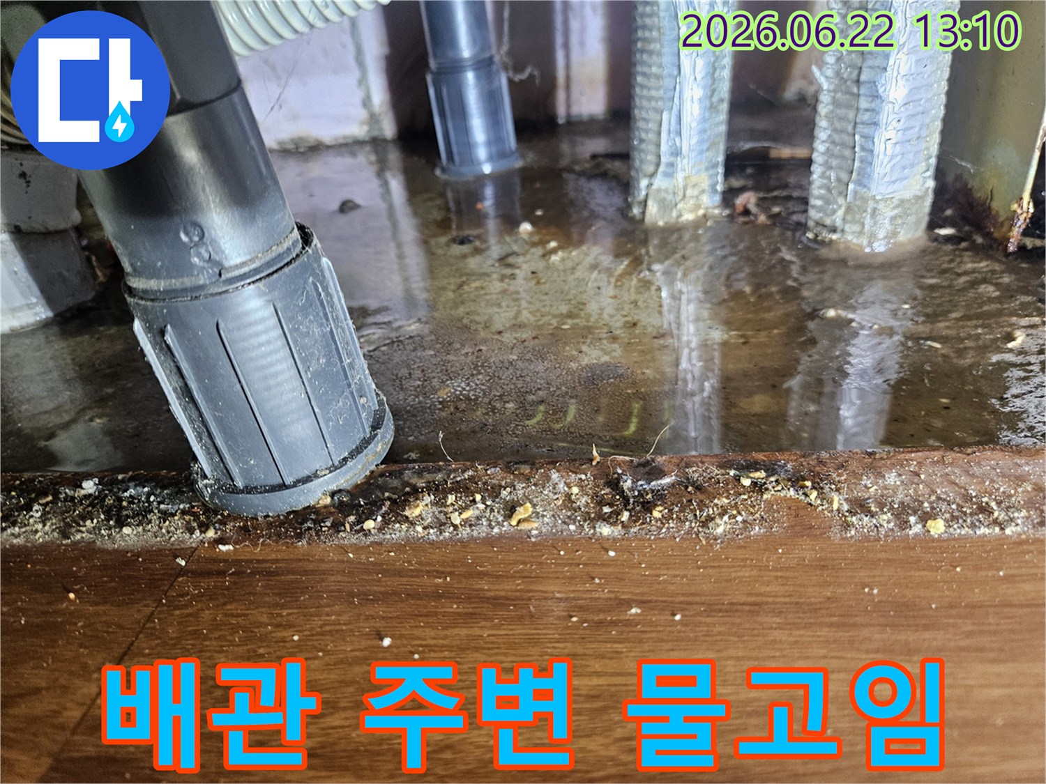 배관 주변 바닥에 물이 고여-오염된 누수 현장의 클로즈업 사진입니다.