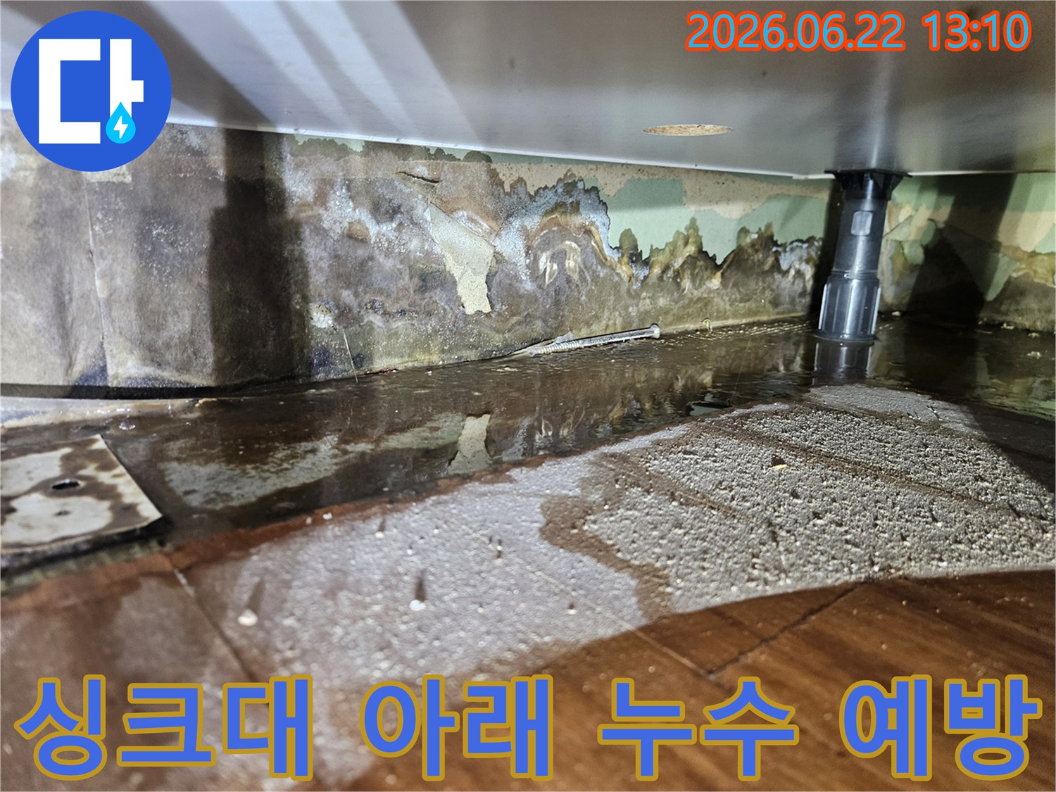 싱크대 아래에서-물이 새어 나와-벽면과 바닥이 젖고-벽지가 손상된-누수 현장-사진