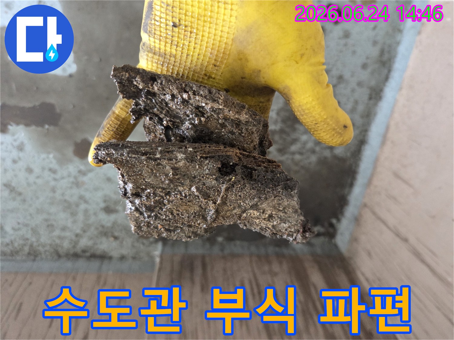 오래된-건물의-배관에서-발견된-심각하게-부식된-파편을-작업자가-직접-보여주며-누수-원인을-설명하는-장면입니다.