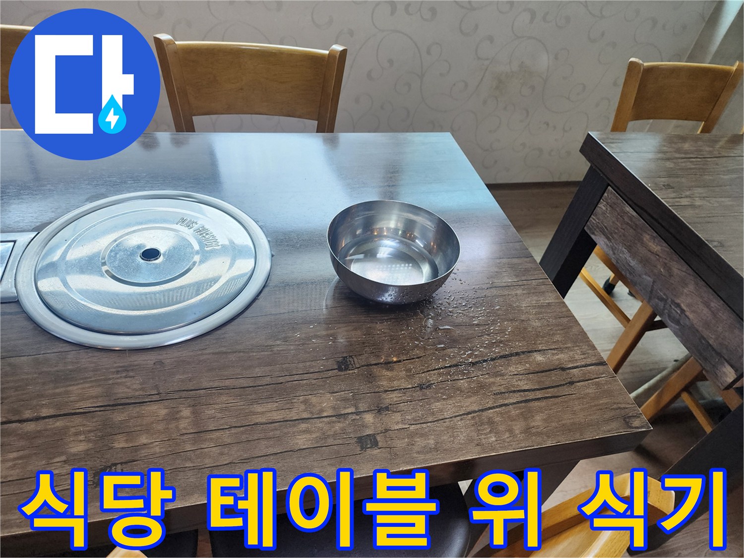 나무 재질의 식탁 위에 놓인 스테인리스 그릇과 냄비 뚜껑