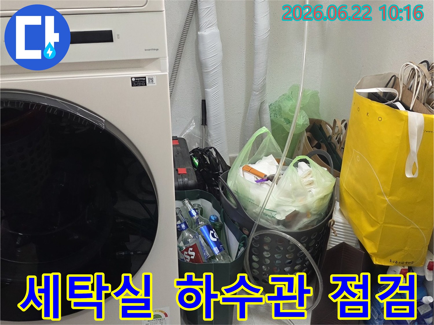 세탁기-옆-벽면에-위치한-단열된-하수관의-상태를-육안으로-면밀히-살펴보는-기술자의-모습