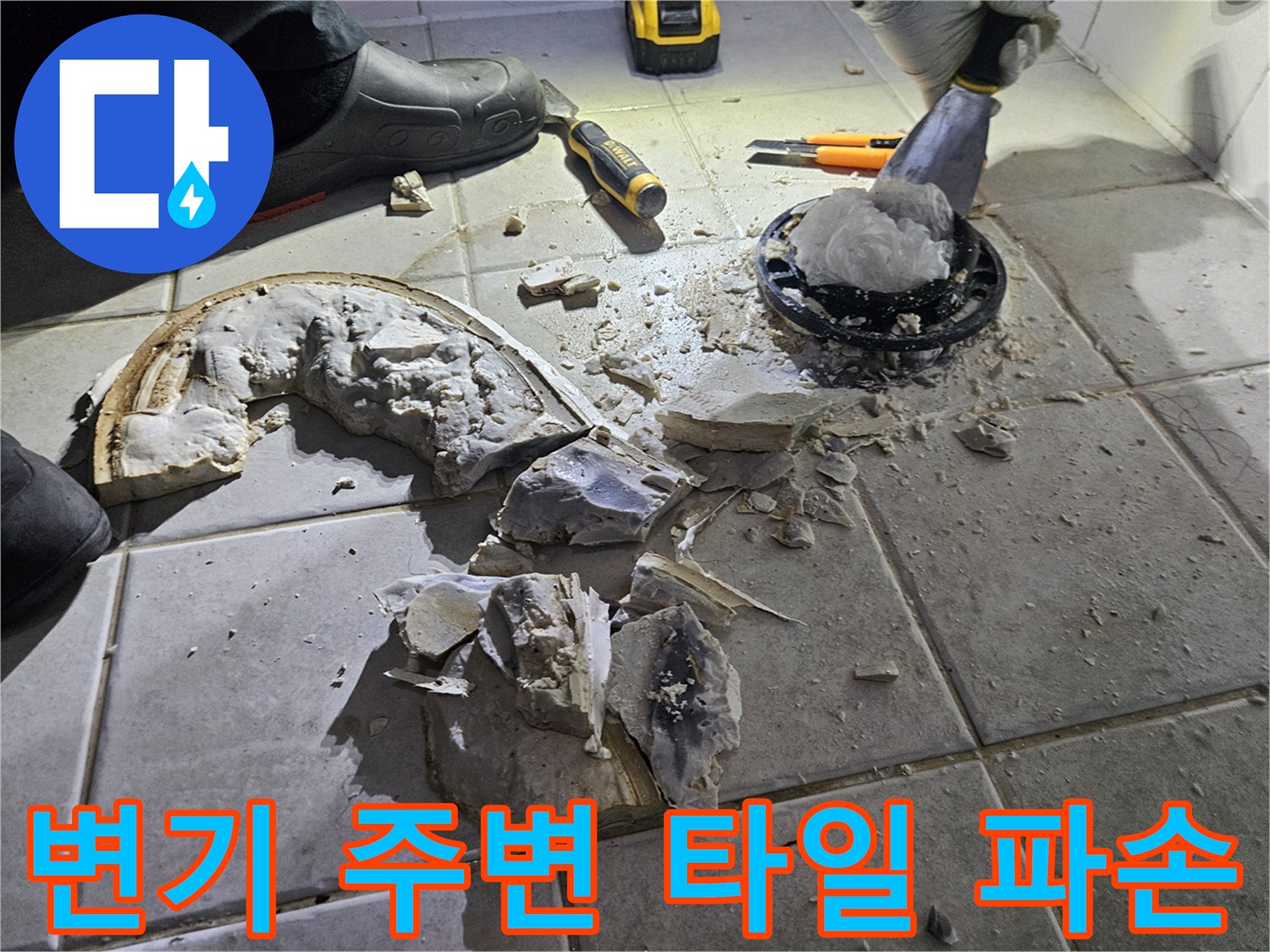 변기 배관 주변의 파손된 타일과 시멘트 조각들