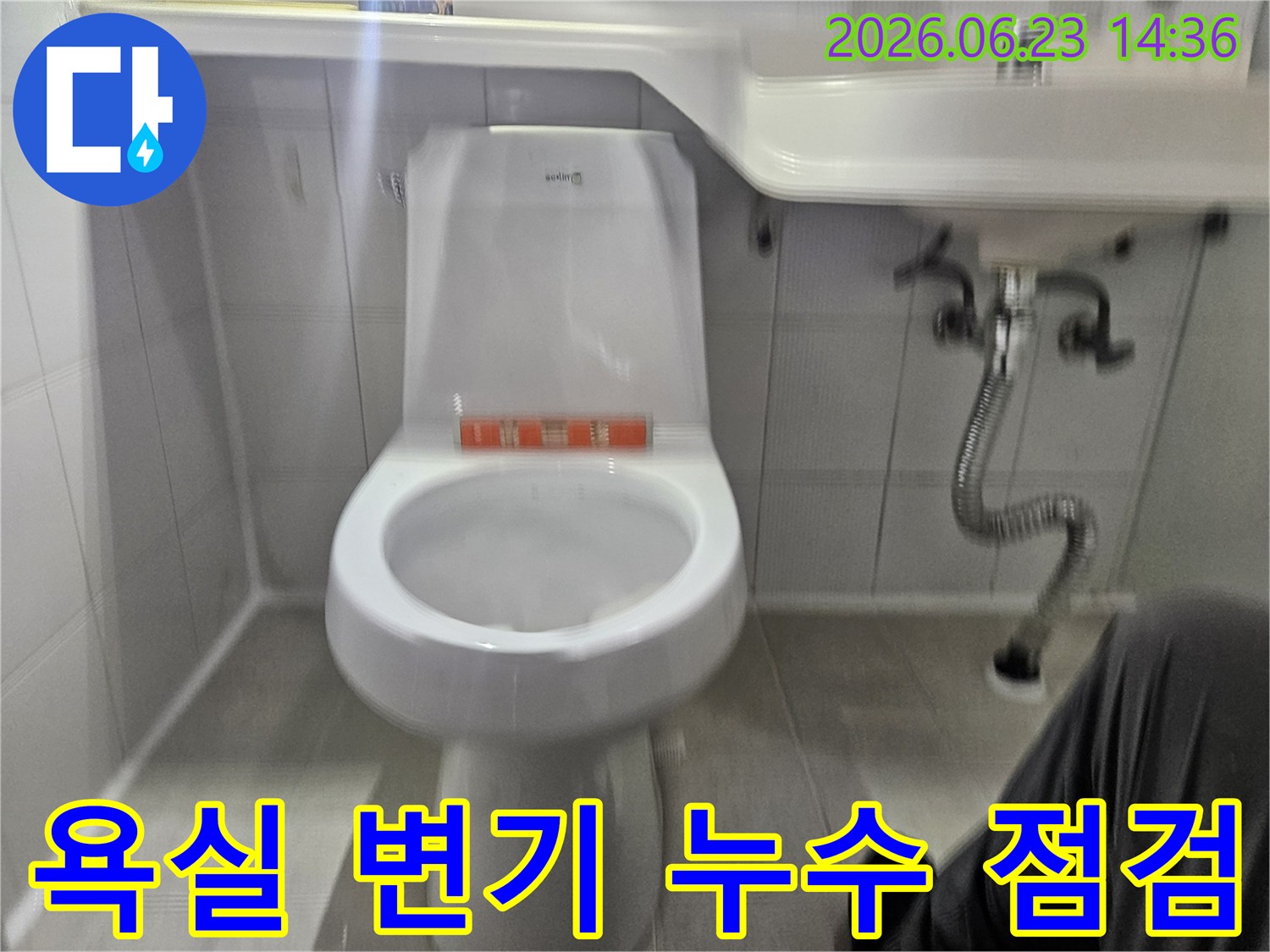이 사진은 욕실 변기 주변에서 발견된 물샘 현상을-전문가가 면밀히 조사하는 과정을 담고 있습니다.